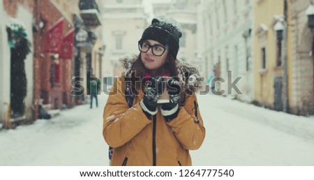 Beautiful happy woman walks around the city drinking coffee in winter snow city. Slow motion 4k RAW