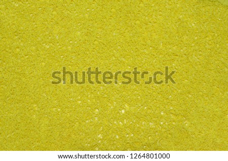 Yellow background of bright plastic shavings, pile of rubber foot pad close up. Thin long elastic bands, snakes interlacing, threads, laces