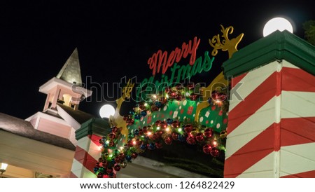 Merry Christmas sign with colorful ornaments and gold reindeer decoration on the top of a striped archway with lights.