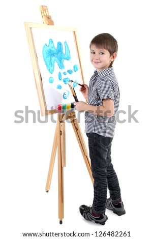 Little boy painting paints picture on easel isolated on white