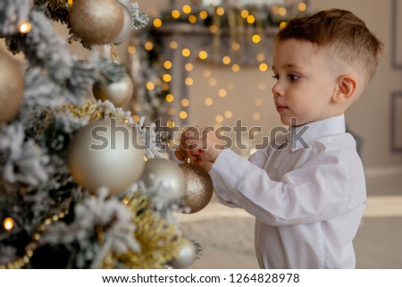 little boy decorates a Christmas tree for Christmas.