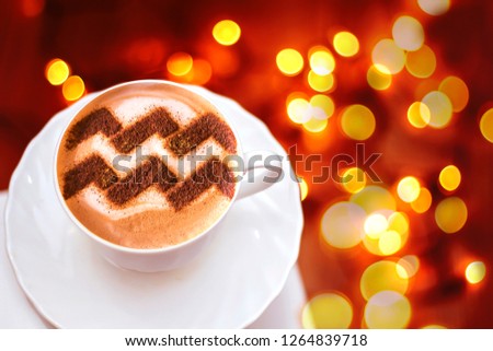 a cup of cappuccino coffee with a pattern of the aquarius aquarius zodiac sign on milk foam