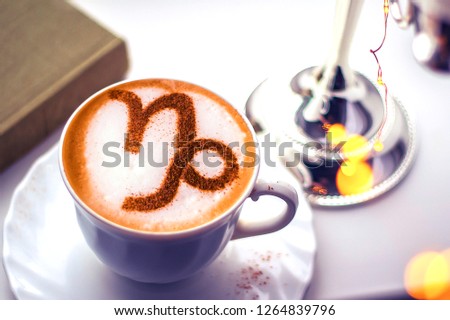 A cup of cappuccino coffee with a zodiac sign pattern Capricorn Cinnamon on milk foam