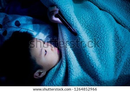 asian chinese boy playing smartphone on bed, watching smartphone, kid use phone and play game, child use mobile, addicted game and cartoon, 

