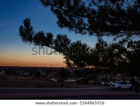 Sun reflecting off of Denver, Colorado tall building as sunset with deep blue sky, orange horizon,