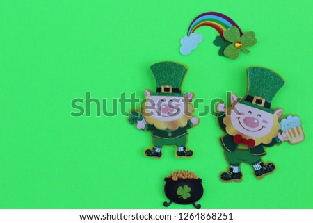 two leprechauns one dancing holding a beer with a rainbow and a pot of gold on a green background with writing space