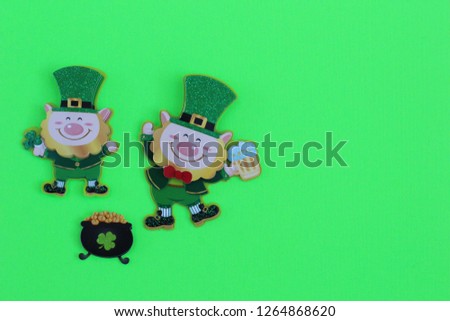 two leprechauns one dancing holding a pint of beer laying flat next to a pot of gold on a green background with writing space