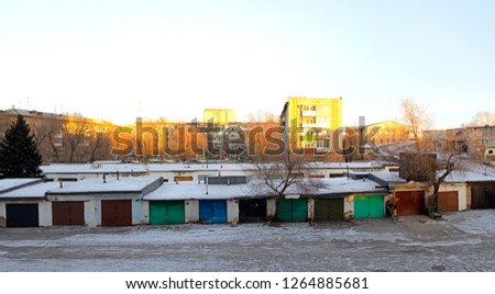 Ordinary Russian apartment buildings and garages for cars. The golden hour, before sunset.