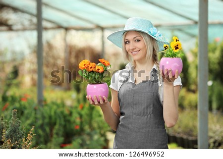 Young female gardener holding flower pots in a garden