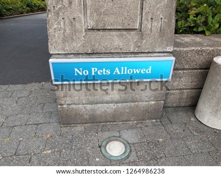 blue no pets allowed sign on cement wall