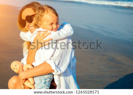 mother kisses her daughter in the morning on the beach