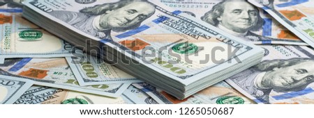 A pack of American dollars on the background of hundred dollar bills.