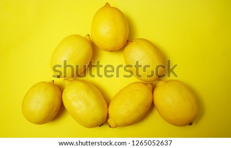 lemons lie in the form of triangle . yellow paper background. 