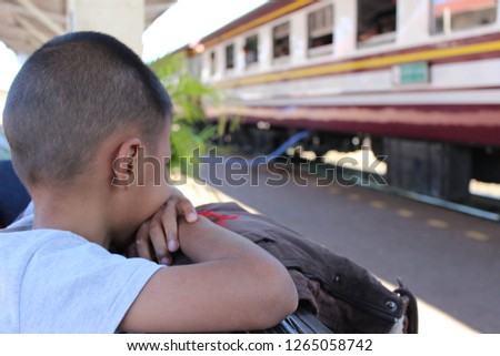 The little boy sat looking at the train in low light