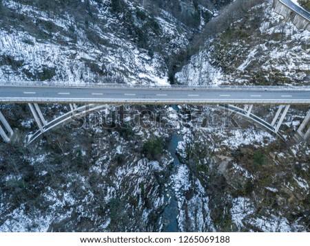Aerial view of road bridge in Switzerland over a deep valley in winter with snow covered ground. Icy conditions.