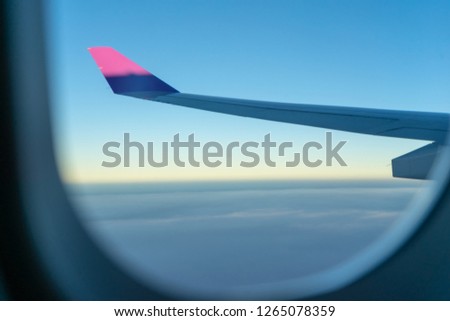 Aerial view from airplane window over clouds  with airplane's wing and blue sky background. Copy space available for your text message or content.Soft focus photo.