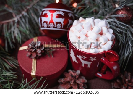 New year's gift with coffee and marshmallows. A box with a drink and sweets. Christmas decorations and balloons. Delicious drink under the tree with cones.
