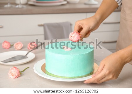Woman decorating fresh delicious birthday cake in kitchen, closeup