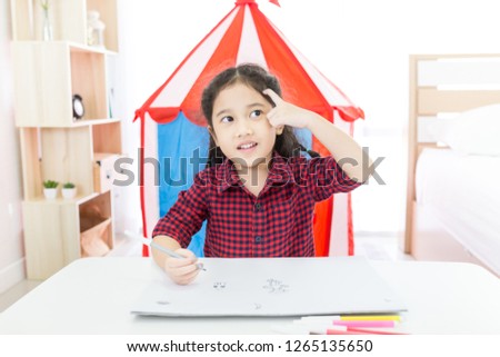attractive Asian children leaning to drawing cartoon in her bedroom, she think and get idea in art work time, felt tip pen, development education activity