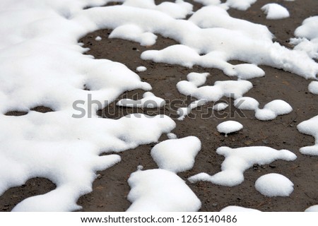 Winter background. The snow is melting and looking through the ground. Royalty-Free Stock Photo #1265140486