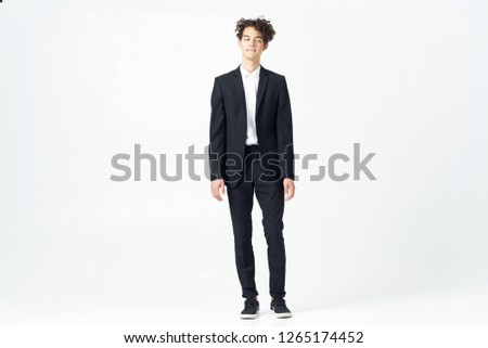 Cute curly guy in a suit on a light background            