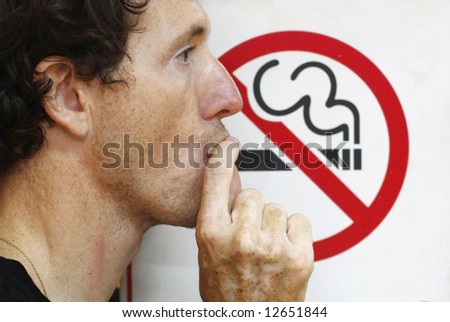 man smoking a no-smoking sign
