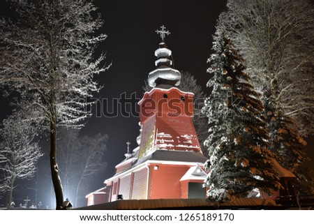 Beautiful illuminated wooden church photography  in the night  winter full of snow Tylicz Poland Royalty-Free Stock Photo #1265189170