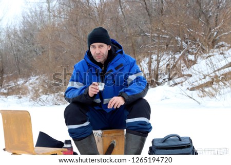 A man with an iron mug in his hand against the background of a beautiful winter nature.