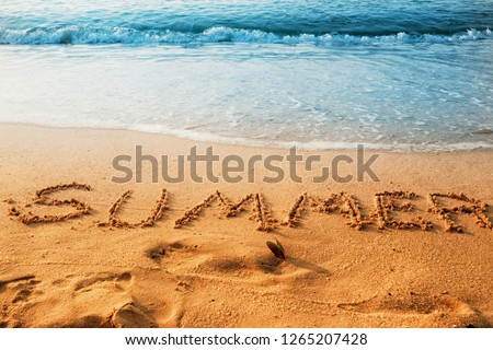 The concept of summer with handwriting on the sand beach with waves blue ocean.