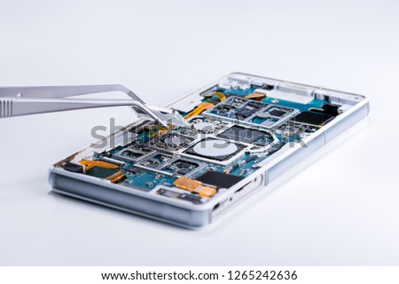 Repairing the smartphone's motherboard in the lab. the concept of computer hardware, mobile phone, electronic, repairing, upgrade and technology. Royalty-Free Stock Photo #1265242636