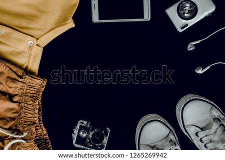 Top view preparation for travel,trip vacation, tourism, extreme sports mock up of smart  phone, camera, action camera, sneakers, clothes, earphone on table. Travel concept background with copy space.