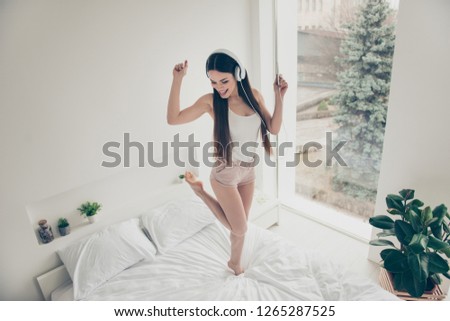 Above high angle view of nice attractive lovely sweet winsome adorable cheerful positive slim straight-haired lady dancing on bed having fun in light white interior room