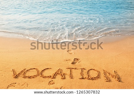 The concept of handwriting, vocabulary, vocation on the sand beach, and blue waves ocean background.
