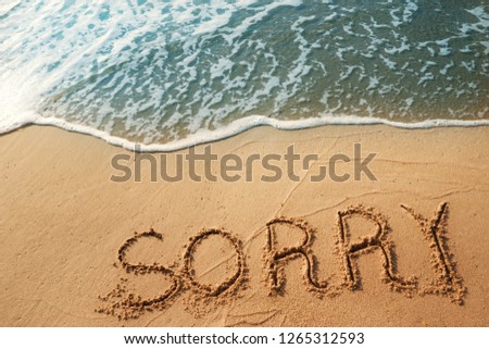 The concept of handwriting, vocabulary, sorry on the sand beach and blue waves ocean.