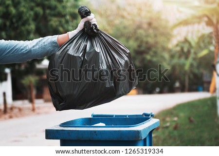 hand holding garbage black bag putting in to trash Royalty-Free Stock Photo #1265319334