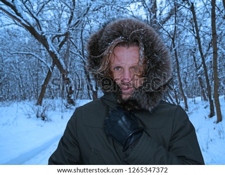 Portrait of a beautiful young man in a hood in a winter snowy forest
