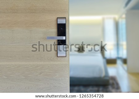 Digital door lock installed on wood door for security and access the room. Door wood texture with electronic door lock opened in front of blur bedroom. Selective focus.