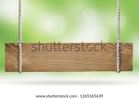 Wooden sign hanging on a rope on natural green background