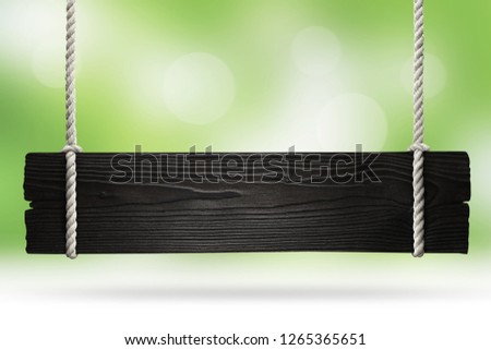 Wooden sign hanging on a rope on natural green background
