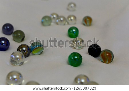 
Close-up of multicolored Christmas beads on a white canvas with a soft blurred background. Beads are scattered in a chaotic manner.