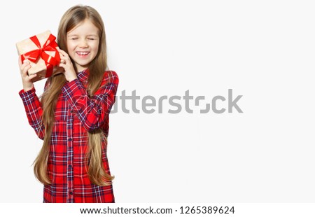 A little girl holds a gift with a red ribbon in her hand.