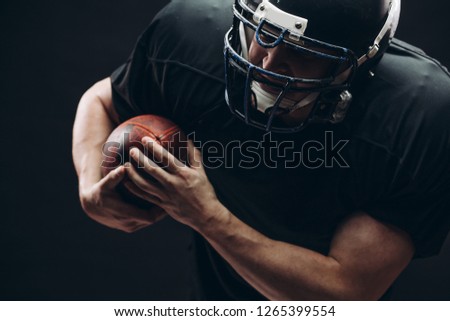American football player with helmet and armour passing a ball while running on field at night