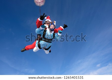 Christmas skydiving. Santa Claus and girl are flying in the sky.