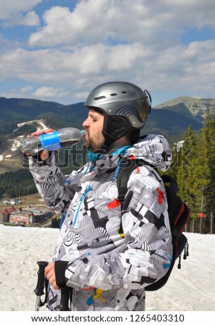 Bukovel, Ukraine - May 2018: Ski resort "Bukovel". A man in ski equipment before descending. Skier drinking from a bottle.