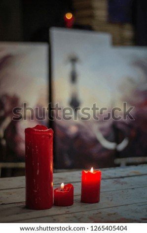 Beautiful and diverse subject. Several beautiful, red candles burn on a natural base and foundation on a dark background.