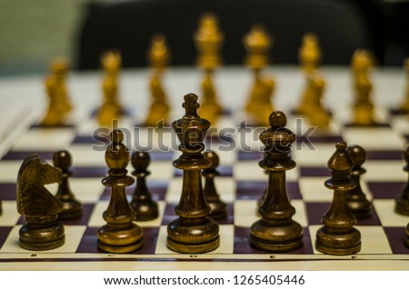 Beautiful and diverse subject. Beautiful wooden lacquered chess pieces on a chessboard at close range in a dark interior.