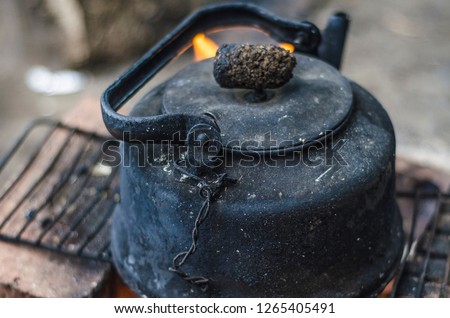 Beautiful and diverse subject. An old and dilapidated black kettle in the soot of a fire on the fire in nature in the summer afternoon.