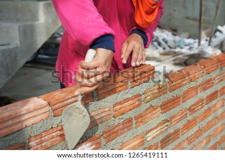 Hands of worker holding old trowel to installing bricks laying at construction site