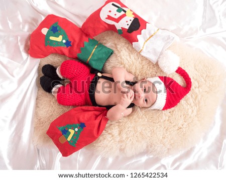 cute four-month baby  santa  with Christmas red dress on white fabric background in lovely action, motherhood and christmas concept