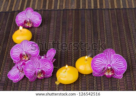 frame with orchid flowers and candles on bamboo mat